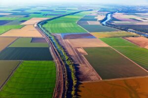 Aerial view of California farmland with a patchwork of fields and a winding river running through the landscape