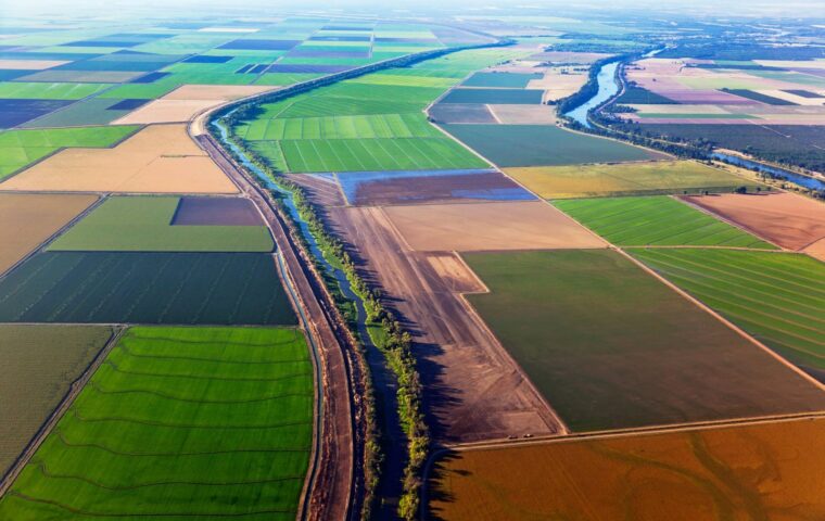 Aerial view of California farmland with a patchwork of fields and a winding river running through the landscape