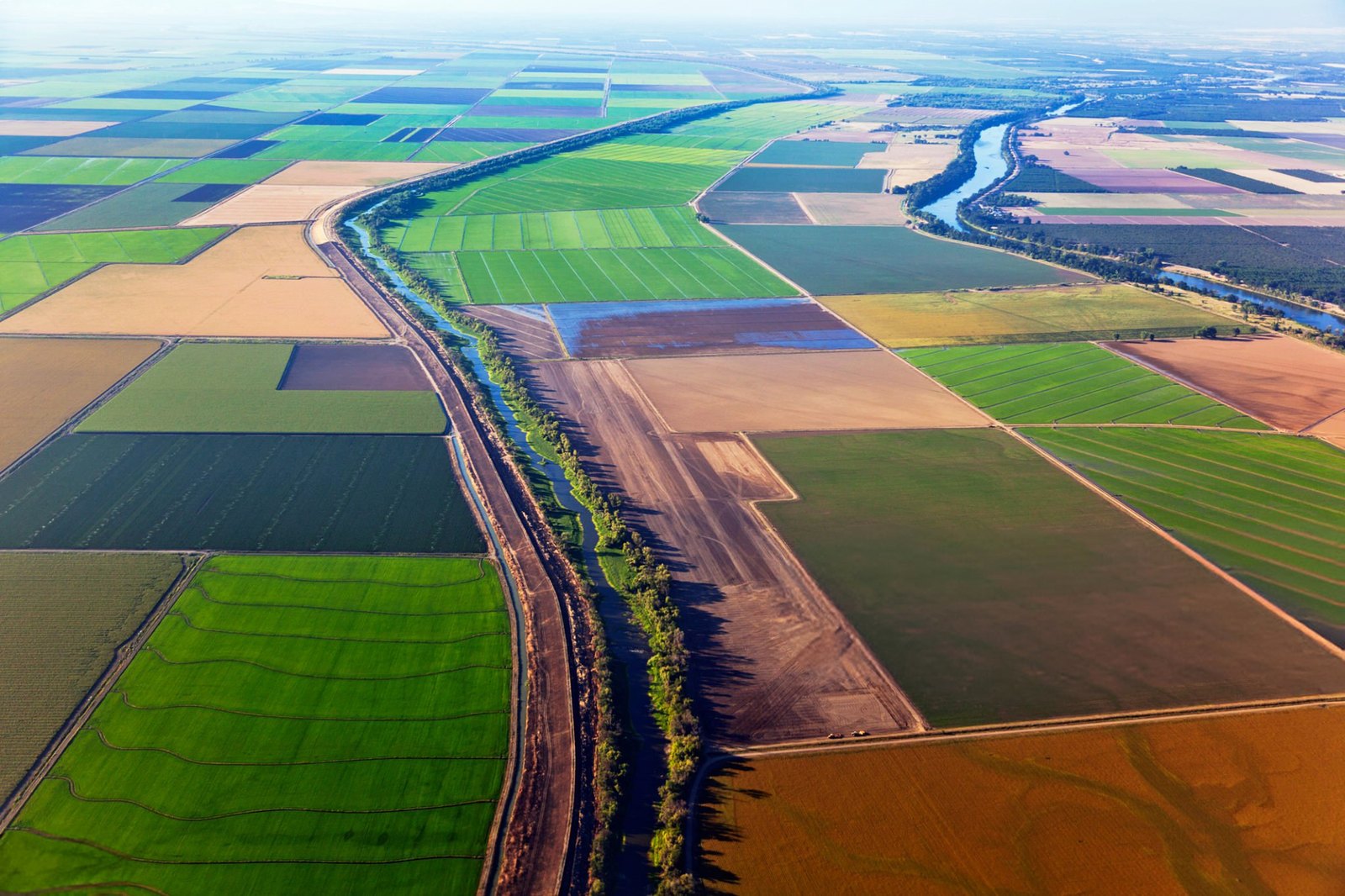 Aerial view of California farmland with a patchwork of fields and a winding river running through the landscape