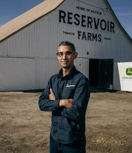 Man standing in front of a Reservoir Farms barn with arms crossed