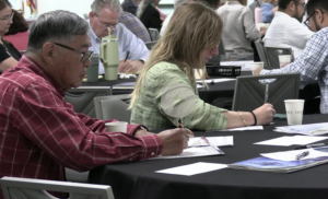 Attendees at a summit session writing notes at tables